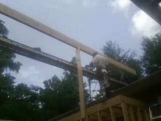 Carpenter setting a ridge beam over a new addition frame — Ice Dam Removal by Roofing Brothers in Williamston