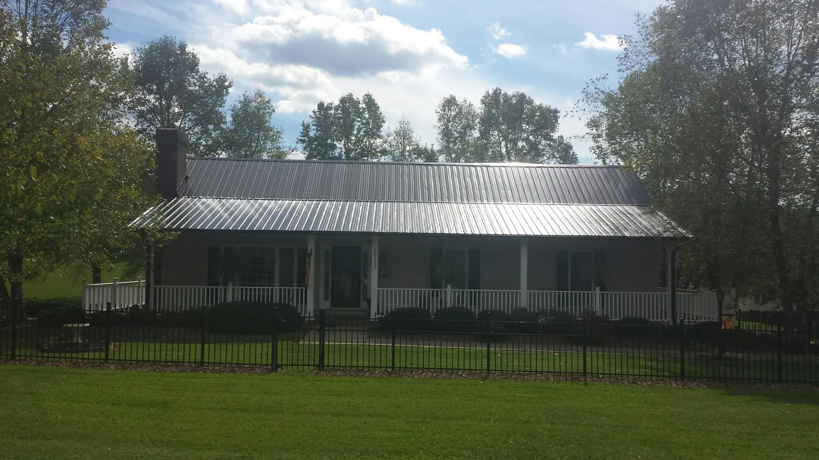 Gray metal roof on a brick ranch with a full width front porch — Gutter Guard Installation work by our crew in Williamston