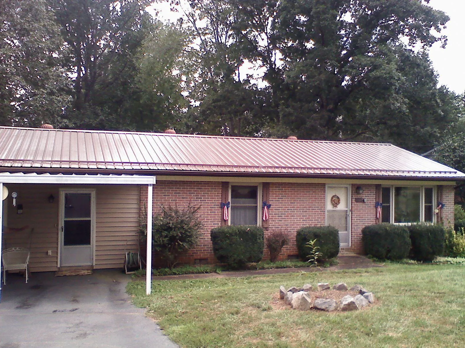 Bronze metal roof and carport on a brick ranch home — Roof Repair work by our crew in Williamston