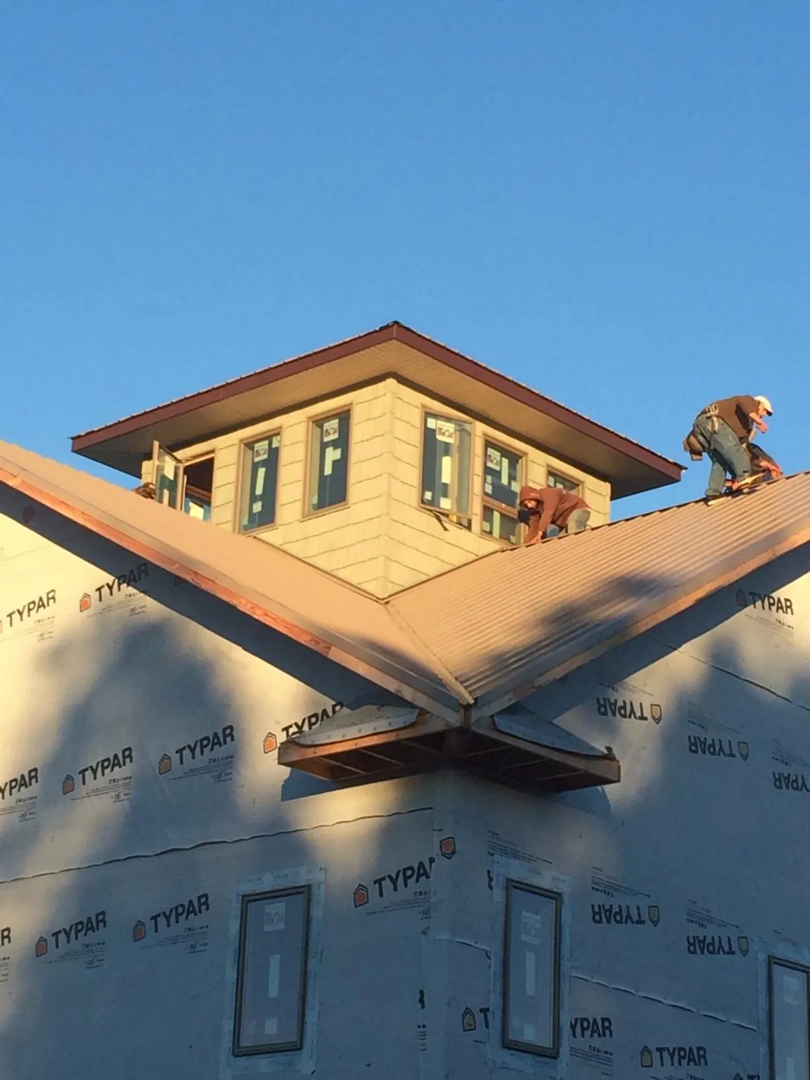 Roofers working around a rooftop cupola on a new metal roof at sunset — Roof Waterproofing in Williamston by Roofing Brothers